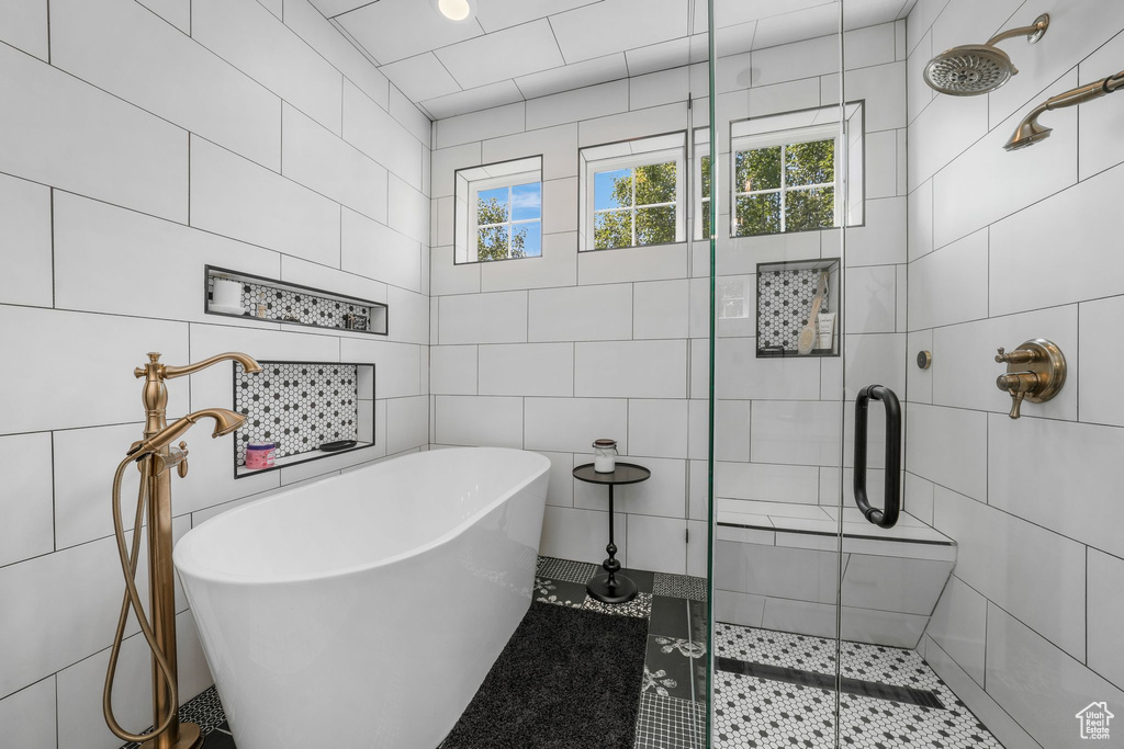 Bathroom with tile walls, a shower stall, a freestanding tub, and tile patterned flooring