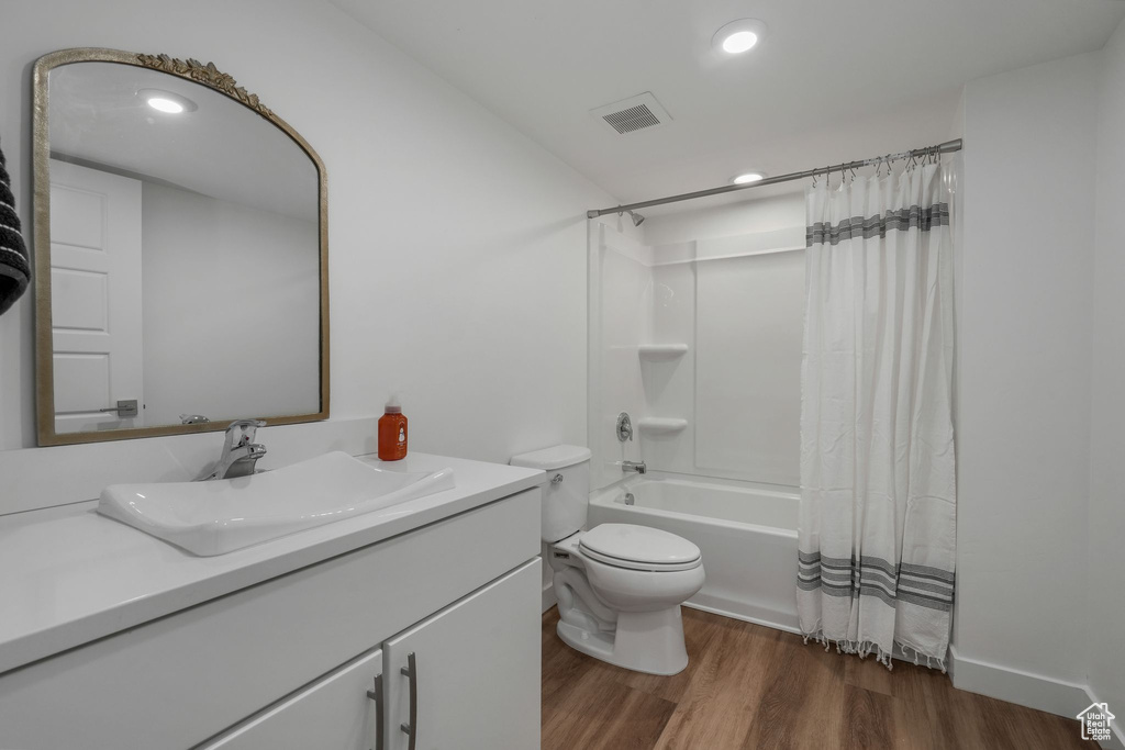 Full bathroom with wood finished floors, vanity, shower / bath combo with shower curtain, and recessed lighting