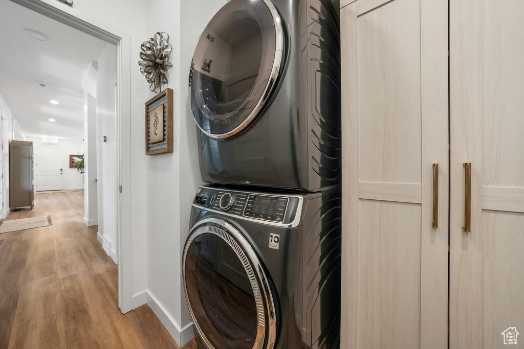 Laundry room with stacked washer / dryer, light wood-type flooring, and recessed lighting
