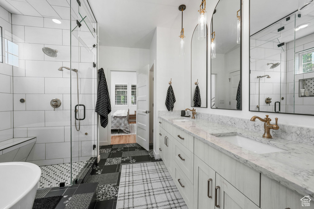 Bathroom featuring a stall shower, double vanity, a freestanding bath, and connected bathroom