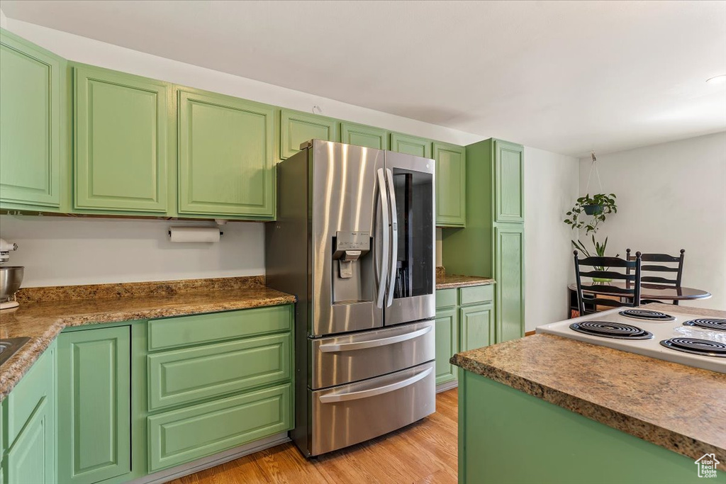 Kitchen featuring stainless steel fridge, light wood finished floors, and cooktop