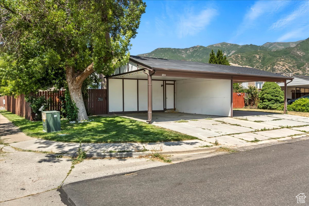 View of front of home with an attached carport, a mountain view, and driveway