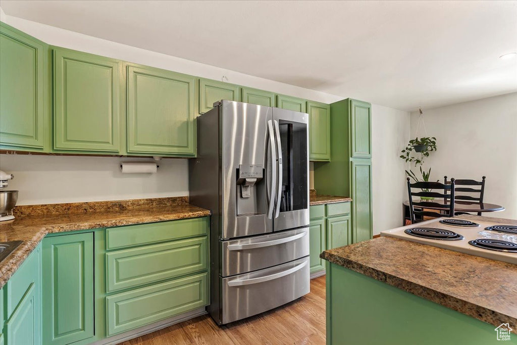 Kitchen featuring stainless steel fridge with ice dispenser, light wood finished floors, stovetop, and dark countertops