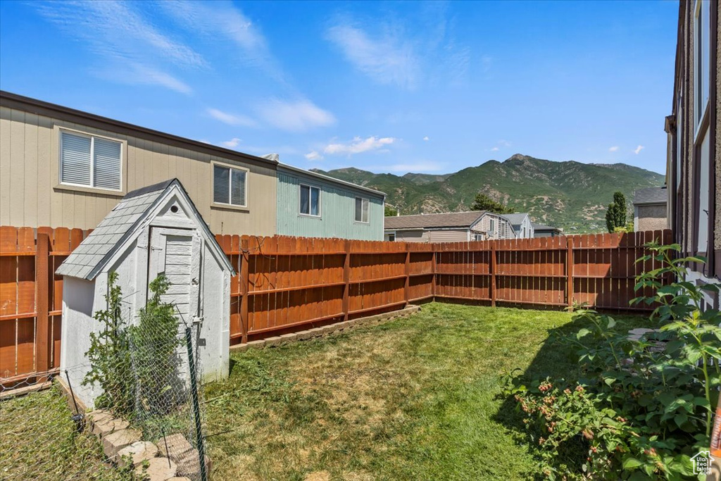 Fenced backyard featuring a shed and a mountain view