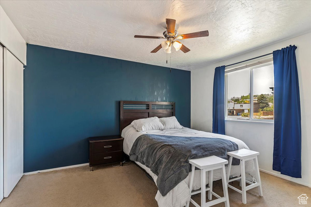 Carpeted bedroom featuring a textured ceiling and a ceiling fan