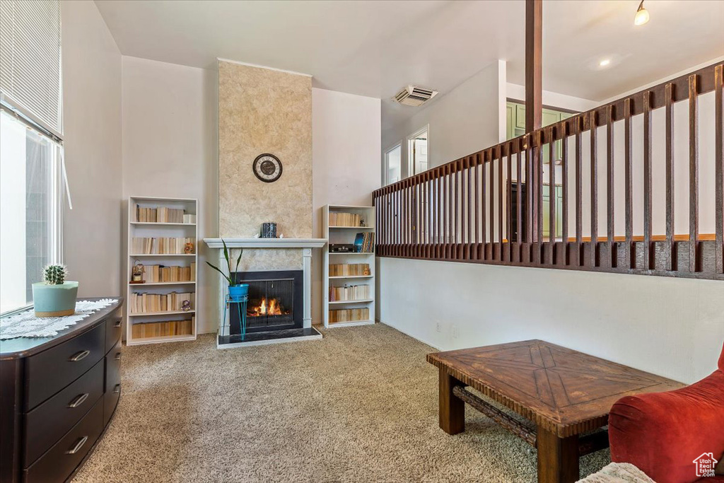 Carpeted living area featuring a warm lit fireplace