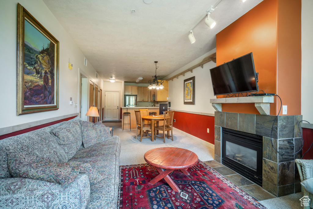 Living room with light colored carpet, a chandelier, and a fireplace