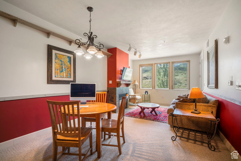 Carpeted dining space featuring a chandelier and baseboards