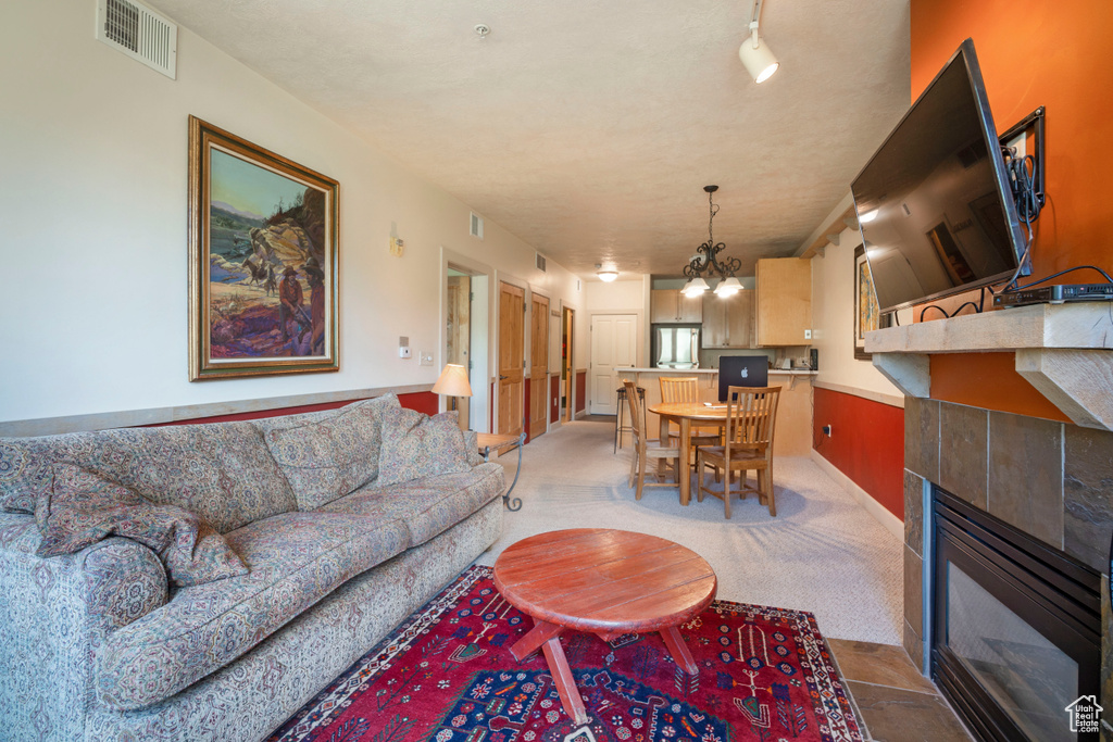 Living room featuring a tile fireplace, a chandelier, and light colored carpet