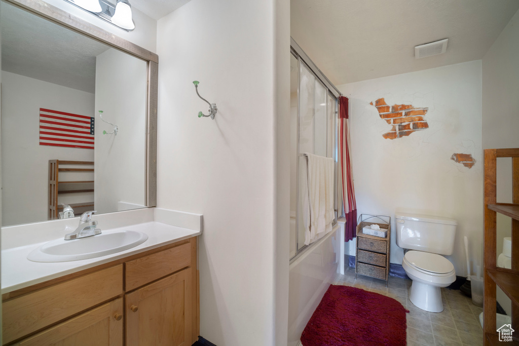 Bathroom featuring vanity, bath / shower combo with glass door, and tile patterned floors