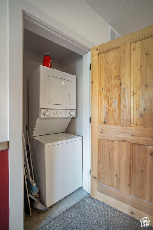 Washroom featuring stacked washing machine and dryer and tile patterned floors