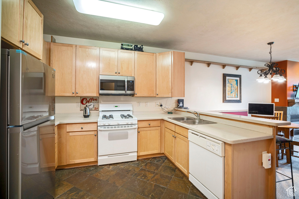 Kitchen featuring stainless steel appliances, light brown cabinetry, and a peninsula