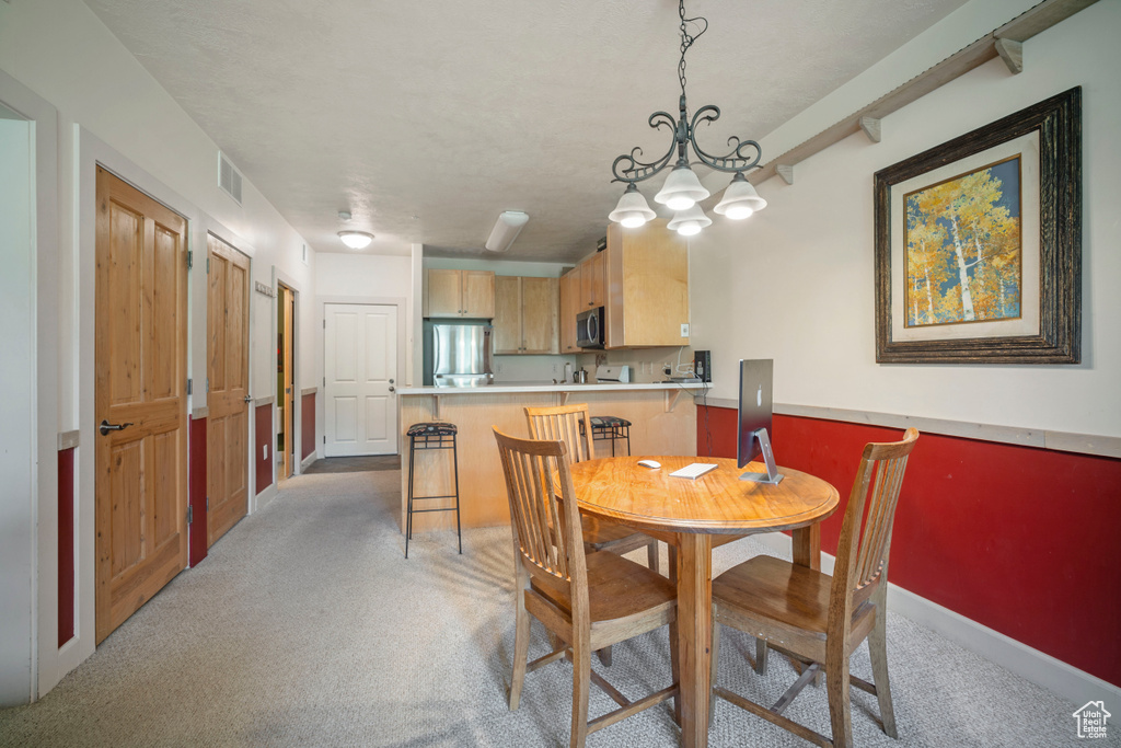 Dining space with light carpet and a chandelier