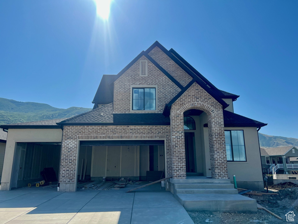 View of front facade featuring brick siding, a mountain view, driveway, and a garage
