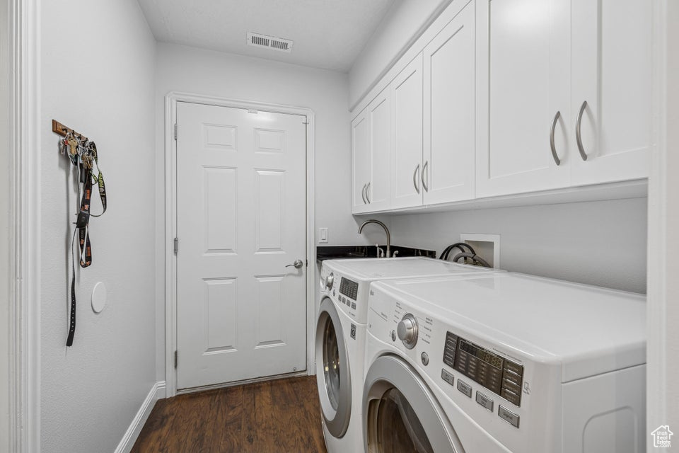 Laundry area featuring cabinet space, dark wood-style floors, and washing machine and clothes dryer