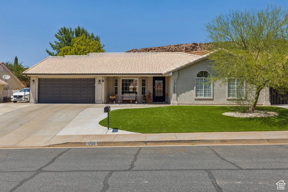 Single story home with a tile roof, a garage, a front yard, and stucco siding
