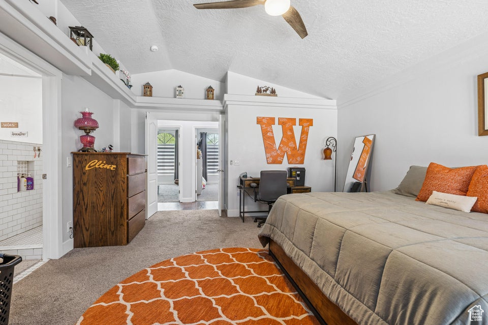 Bedroom with carpet flooring, a textured ceiling, lofted ceiling, ceiling fan, and ensuite bathroom