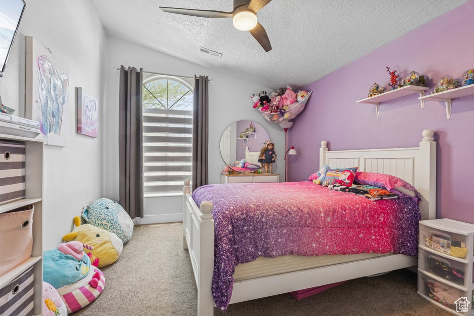 Bedroom featuring carpet floors, a textured ceiling, a ceiling fan, and vaulted ceiling