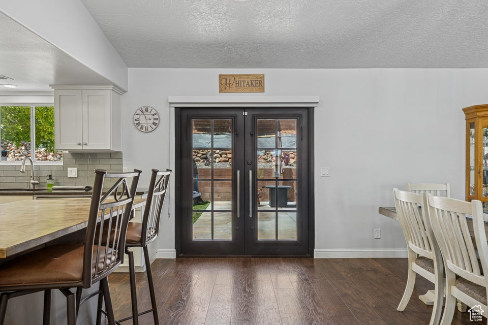 Dining area with french doors, dark wood finished floors, and a textured ceiling