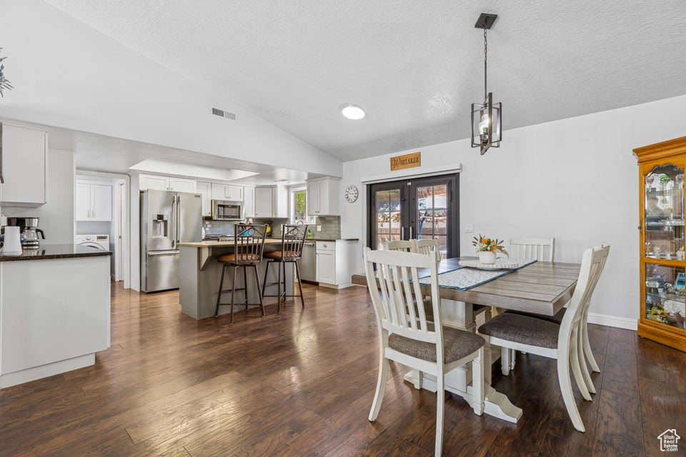 Dining area with lofted ceiling, a textured ceiling, dark wood-type flooring, and washer / dryer