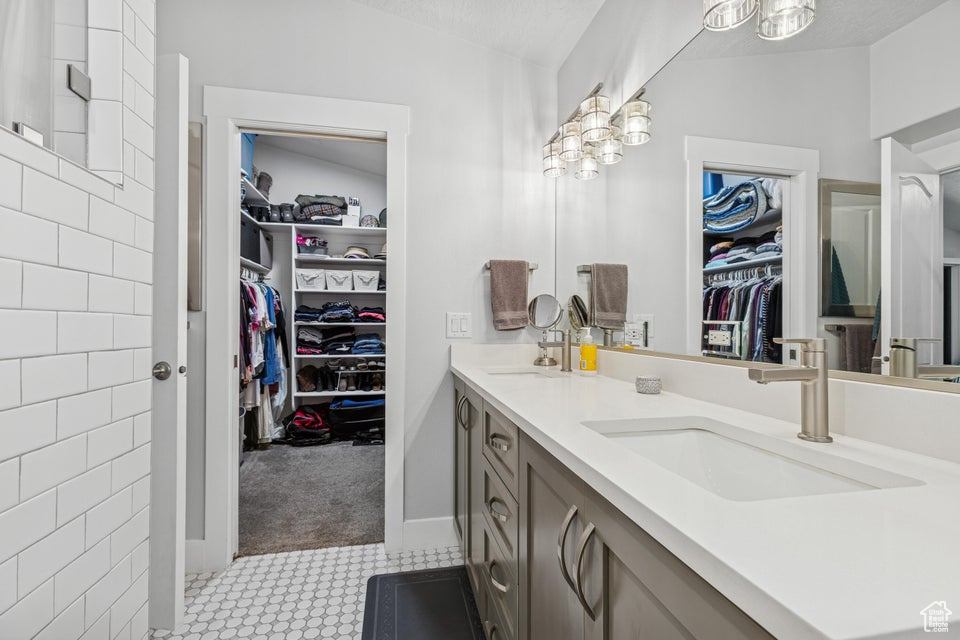 Bathroom featuring double vanity, a walk in closet, and a chandelier
