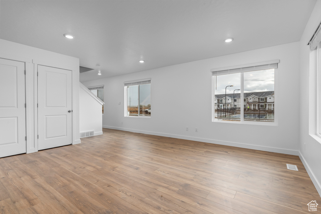 Unfurnished living room featuring wood finished floors, stairs, and recessed lighting