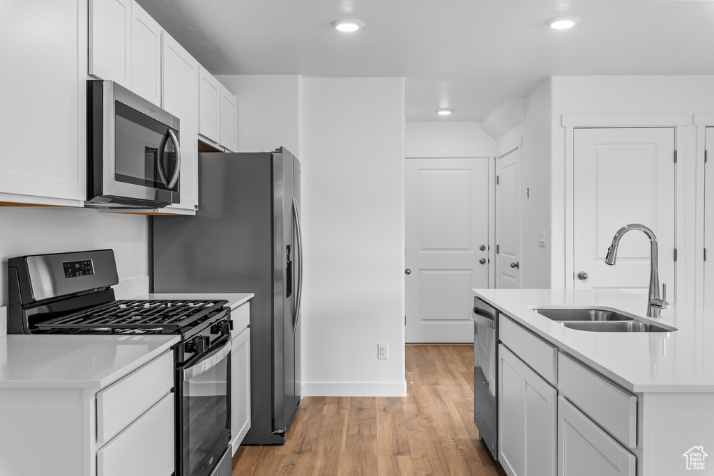 Kitchen featuring appliances with stainless steel finishes, light wood-style flooring, light countertops, white cabinetry, and recessed lighting