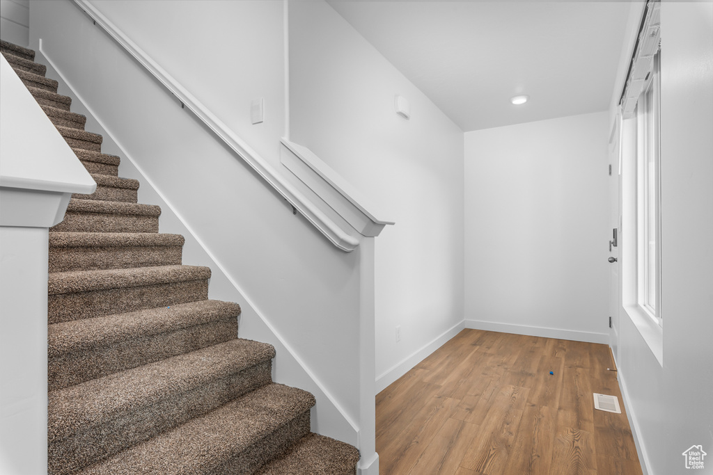 Stairs featuring wood finished floors and recessed lighting