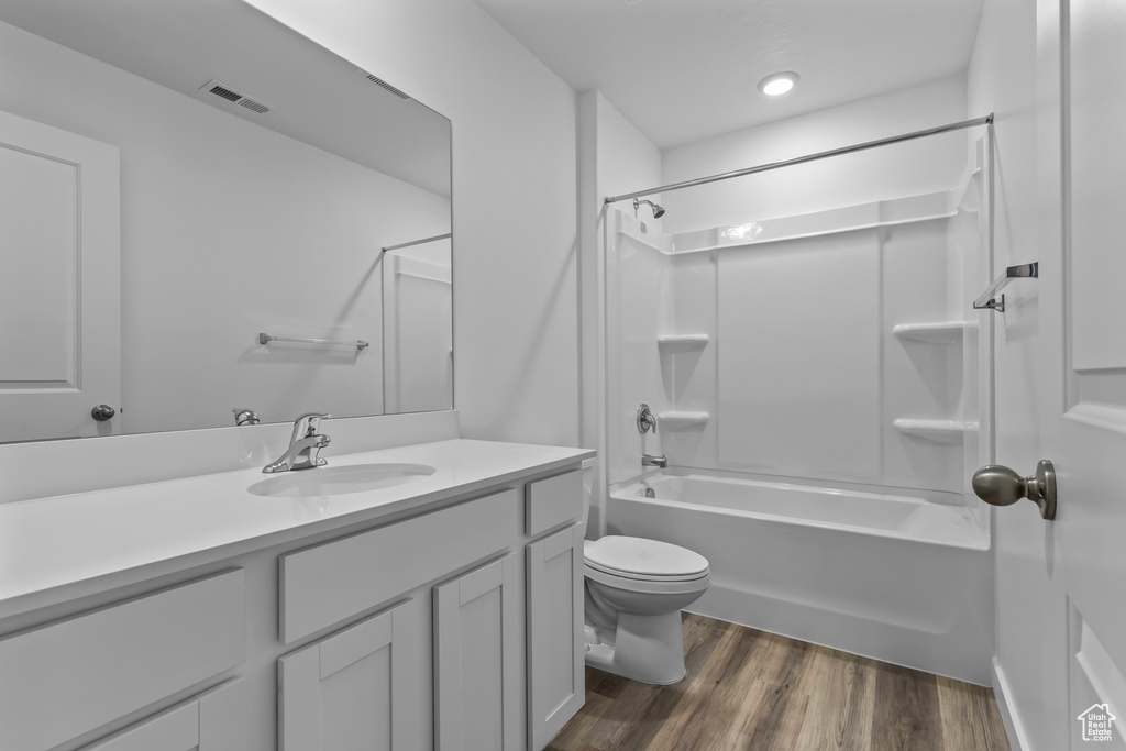 Full bathroom featuring vanity, wood finished floors, and washtub / shower combination