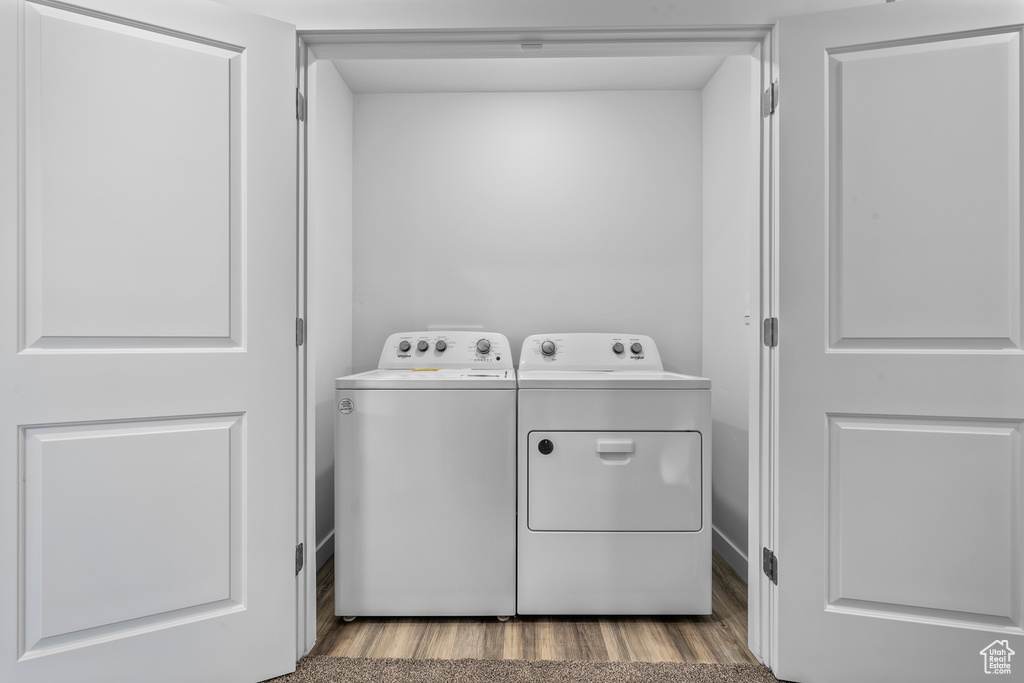 Laundry room with washer and clothes dryer and wood finished floors