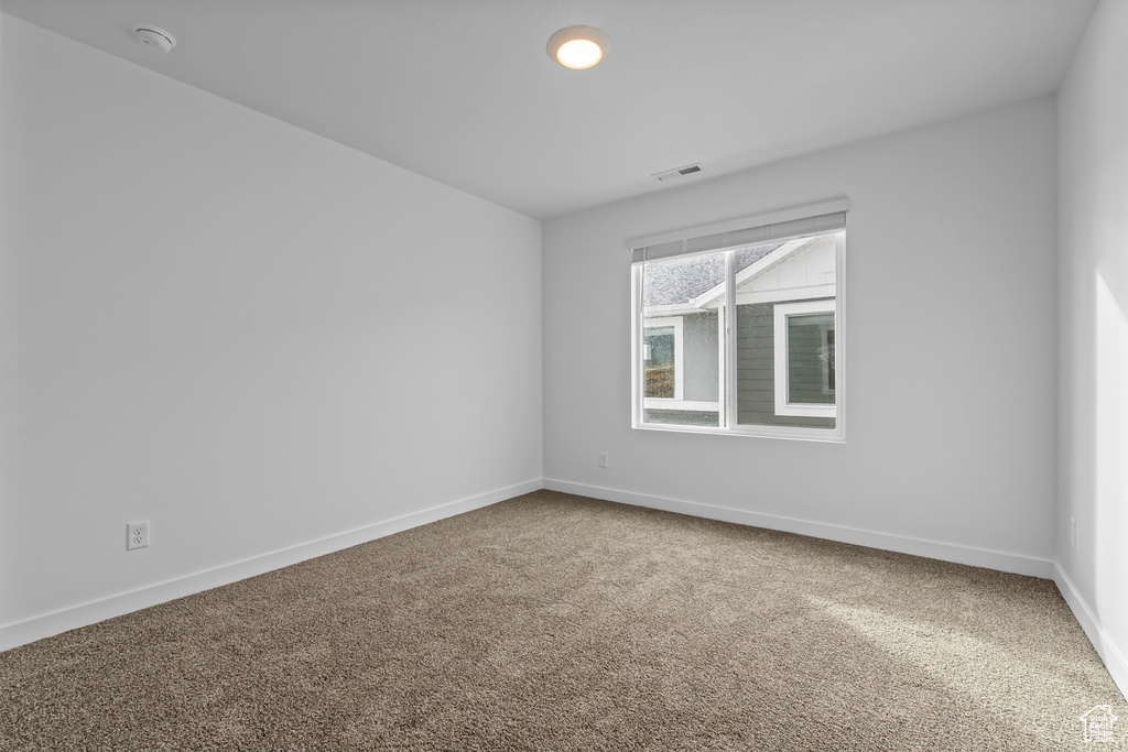 Carpeted spare room with baseboards and a smoke detector