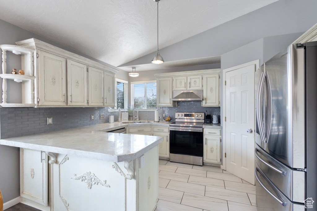 Kitchen with appliances with stainless steel finishes, under cabinet range hood, vaulted ceiling, a peninsula, and tasteful backsplash