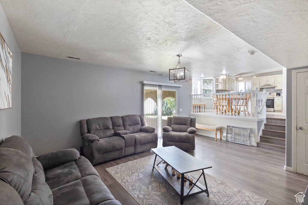 Living area featuring wood finished floors, a chandelier, and a textured ceiling