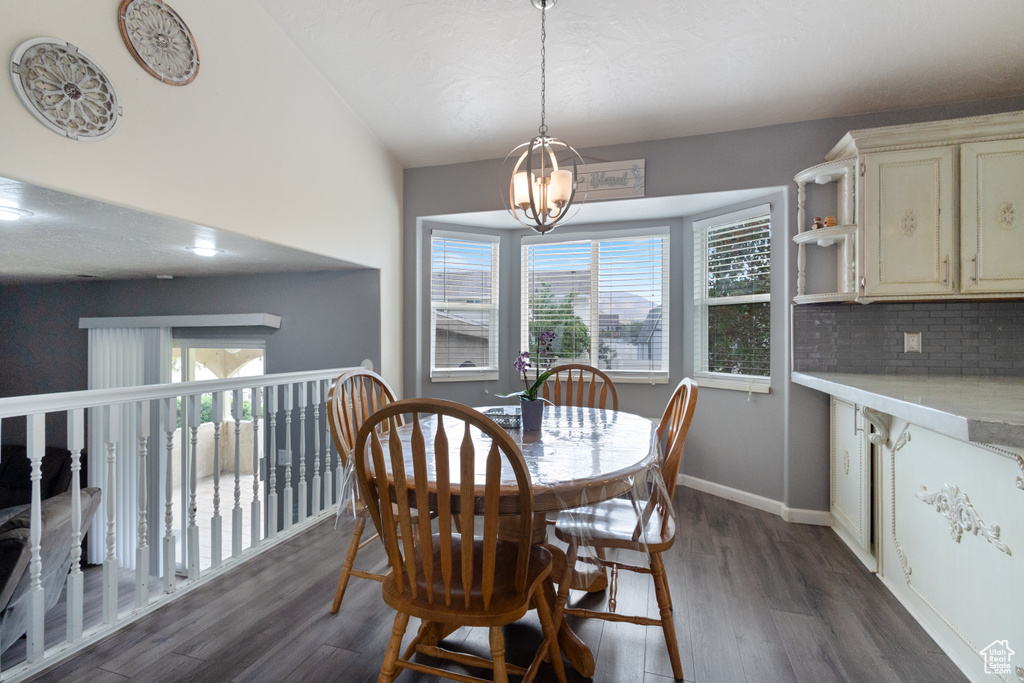 Dining space with healthy amount of natural light, dark wood finished floors, and a chandelier