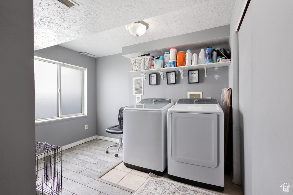 Laundry area featuring washer and clothes dryer and a textured ceiling