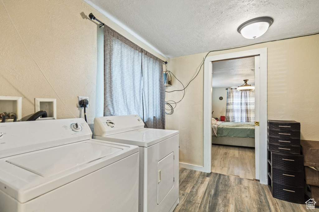 Washroom featuring a textured ceiling, washing machine and clothes dryer, dark wood-style flooring, and a textured wall