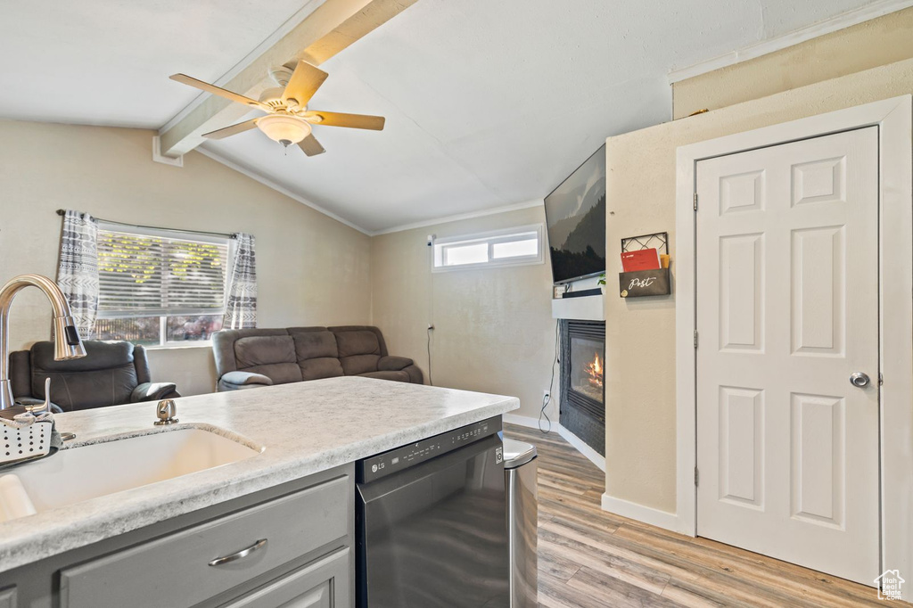 Kitchen with dishwashing machine, gray cabinets, a glass covered fireplace, ceiling fan, and light wood finished floors