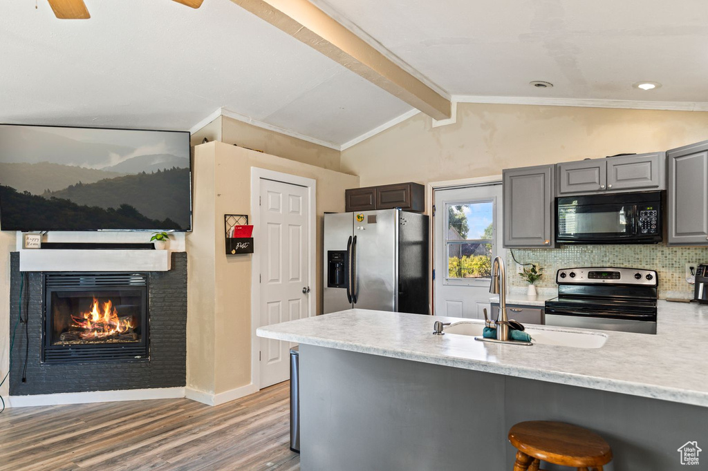 Kitchen with appliances with stainless steel finishes, gray cabinets, light wood finished floors, and light countertops