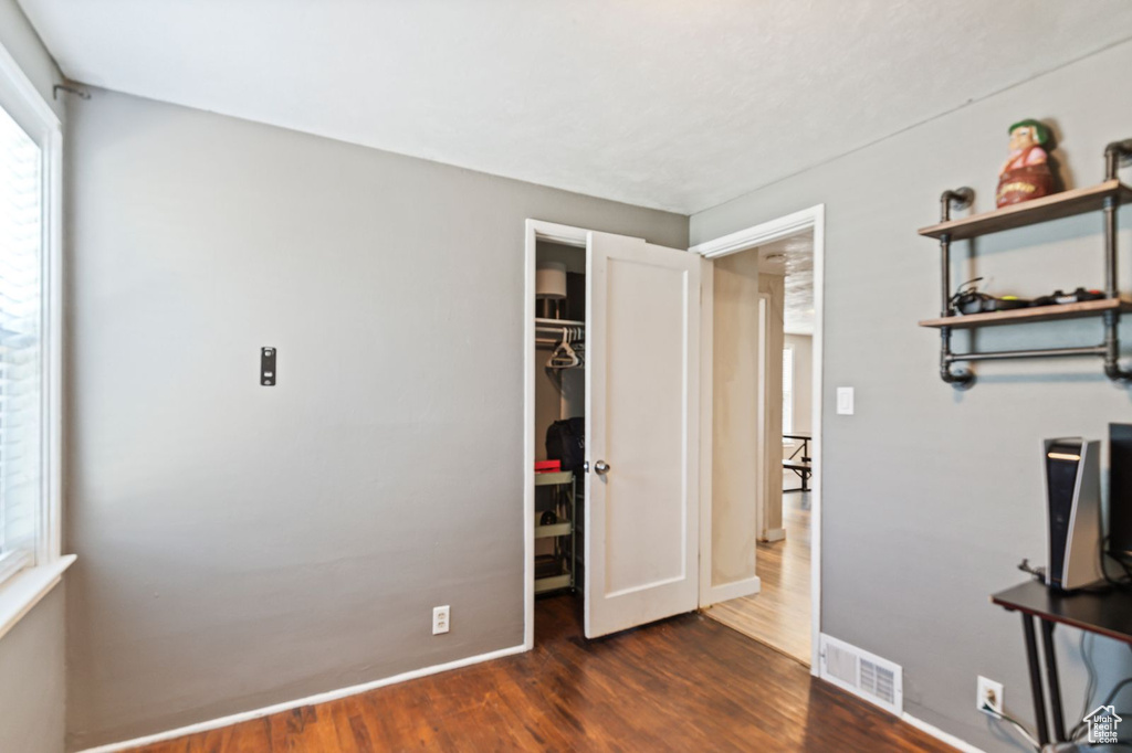 Unfurnished bedroom with dark wood-type flooring, a walk in closet, and a closet