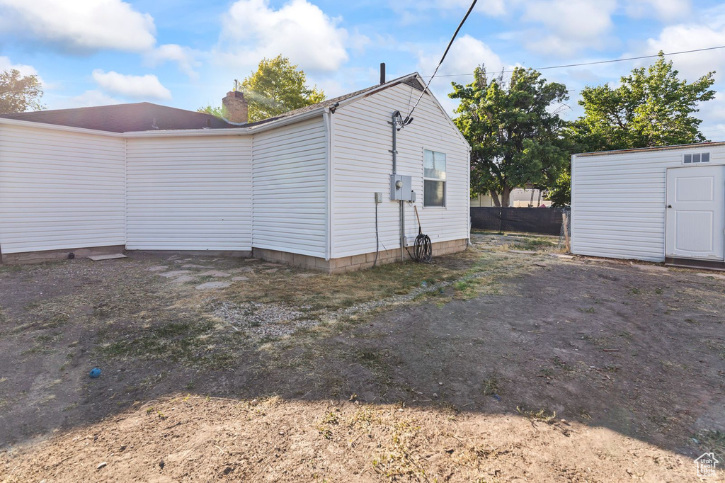 View of property exterior with a chimney and an outbuilding