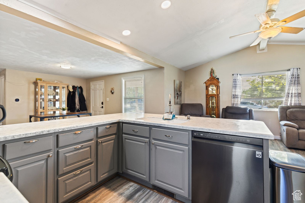 Kitchen featuring gray cabinetry, stainless steel dishwasher, open floor plan, healthy amount of natural light, and vaulted ceiling
