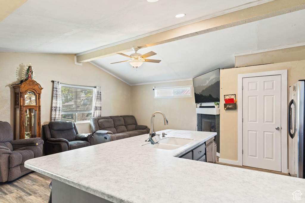 Kitchen featuring light wood finished floors, light countertops, freestanding refrigerator, ceiling fan, and open floor plan
