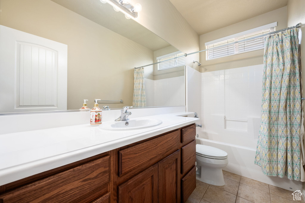 Full bath featuring vanity, shower / bath combo with shower curtain, and tile patterned floors