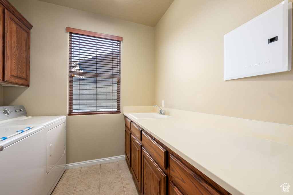 Washroom with washer and clothes dryer, cabinet space, and light tile patterned floors