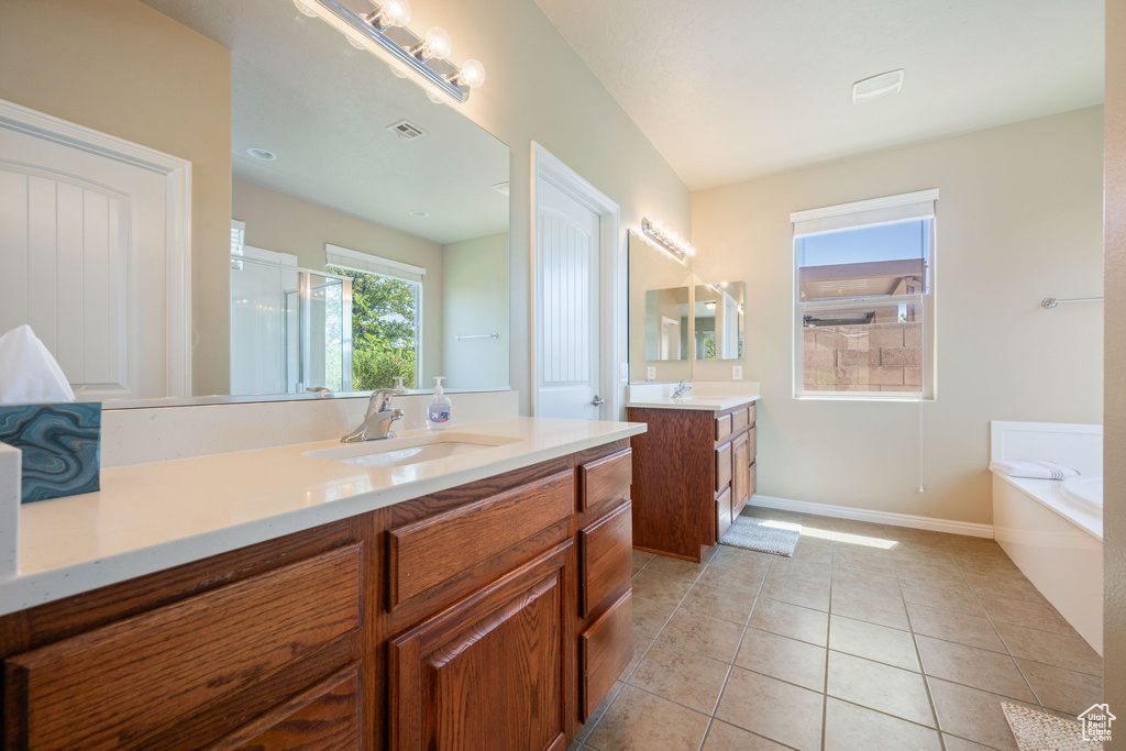 Bathroom featuring two vanities, a garden tub, a shower stall, and tile patterned floors