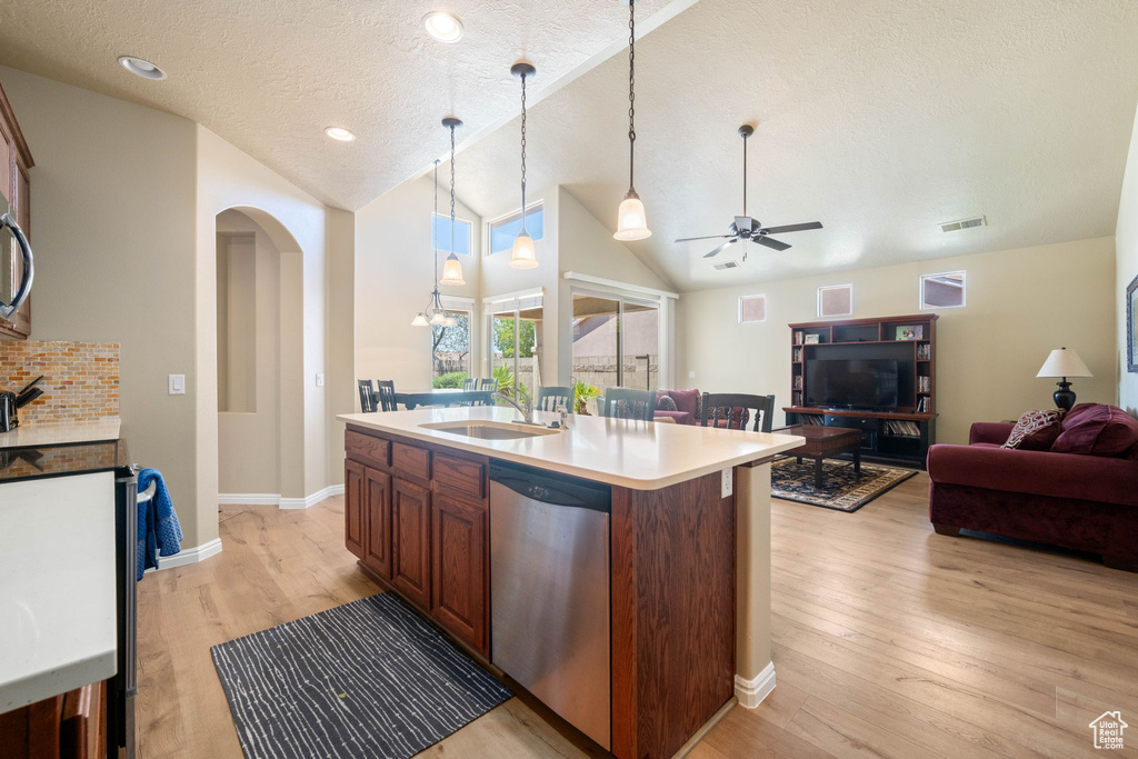 Kitchen with appliances with stainless steel finishes, open floor plan, vaulted ceiling, light wood finished floors, and ceiling fan