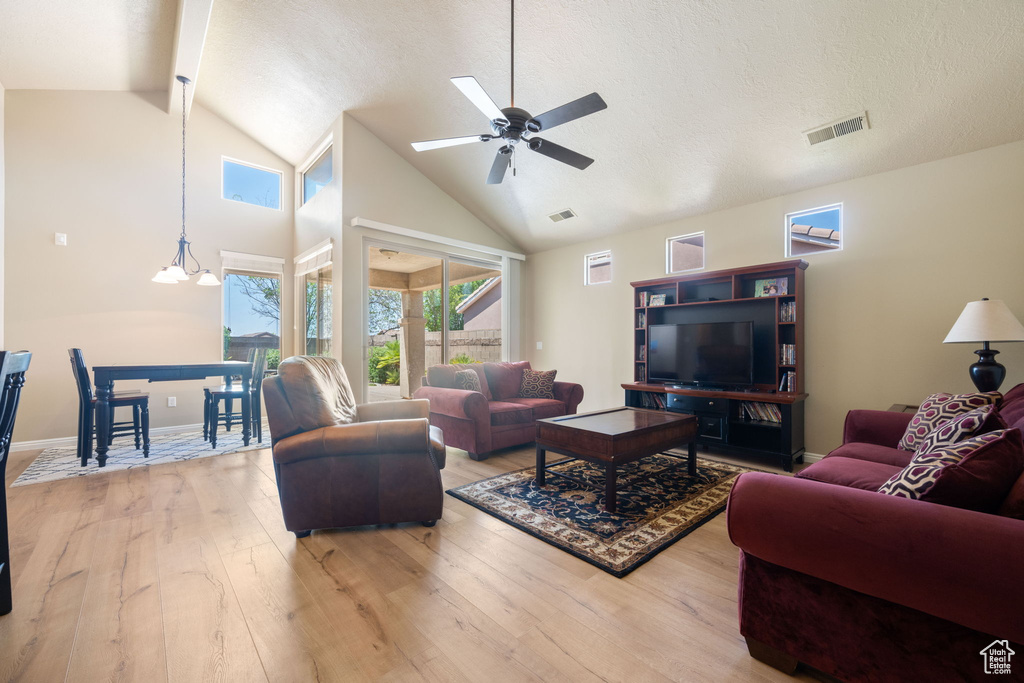 Living area featuring wood finished floors, a ceiling fan, high vaulted ceiling, and a textured ceiling