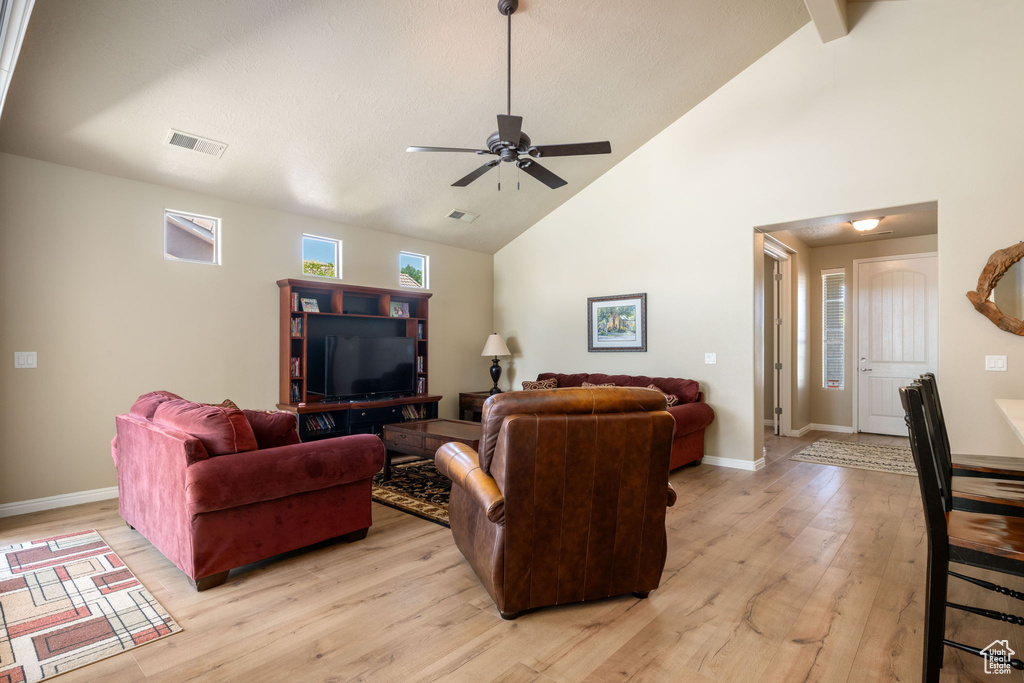 Living area featuring light wood-style floors, high vaulted ceiling, and ceiling fan
