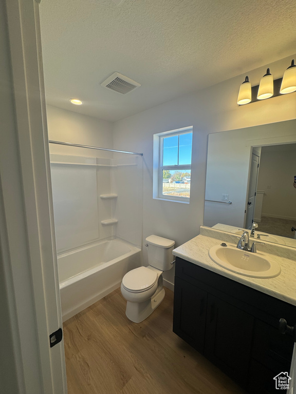 Bathroom featuring wood finished floors, vanity, a textured ceiling, and tub / shower combination