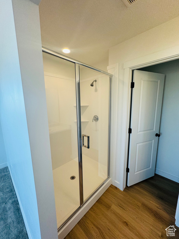 Full bath featuring a stall shower and wood finished floors